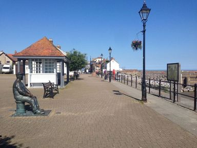 A promenade with benches street lamps a small pavilion a statue and a view of the sea at Anchorage Watchet