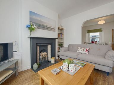 A living room with a grey sofa and a wooden coffee table with cups a teapot and a book at Anchorage in Watchet