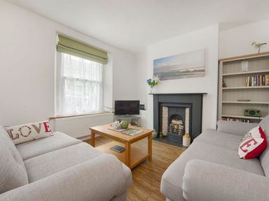 A living room with two grey sofas a wooden coffee table a fireplace and a window with a green blind at Anchorage in Watchet