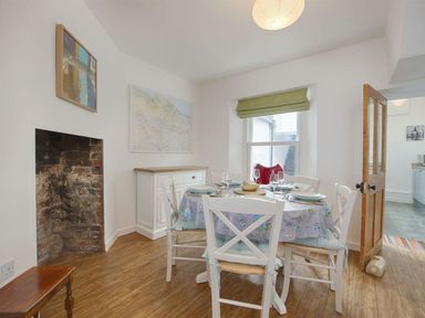 A dining room with a round table set for four chairs a sideboard and a window at Anchorage Watchet