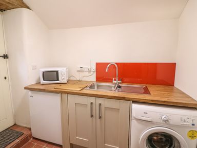 A kitchen area with a microwave a sink washing machine and fridge at Bwthyn Lan in Boncath