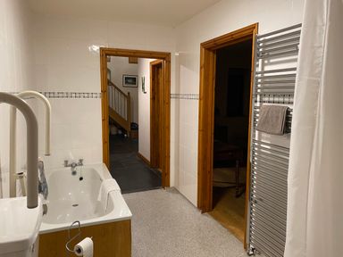 A bathroom with a bathtub a towel radiator and two doorways at Pentrego Isaf in Meifod