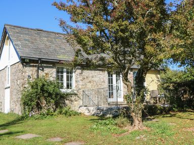 A stone cottage with a slate roof and a tree in front at The Daffodil Shed in Bere Alston