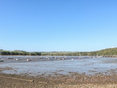 A river with boats anchored and a pebble shore at The Daffodil Shed in Bere Alston