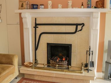 A fireplace with fire irons and various items on the mantelpiece in a living area at Cnoc suan in Aughavas County Leitrim