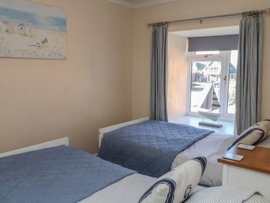 A bedroom with two beds and a window featuring a decorative sailboat at Daisy Lodge in Norwich