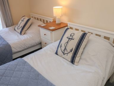 A bedroom with two beds and a lamp on a nightstand at Daisy Lodge in Norwich