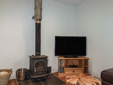 A living room with a stove and television at The Smithy in Blisland