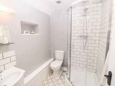 A bathroom with a toilet sink and curved glass shower at 3 Green Terrace in Llangaffo near Newborough