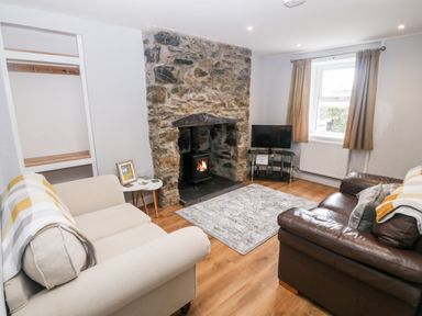 A living room with two sofas a stone fireplace and a television at 3 Green Terrace in Llangaffo near Newborough