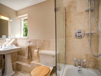 A bathroom with a pedestal sink toilet with wooden seat and a bathtub with shower at Lime Tree in Burford