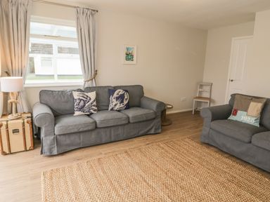 A living room with gray sofas and a woven rug at Ty Taid in Rhosneigr