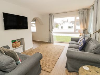 A living room with two grey sofas and a large window at Ty Taid in Rhosneigr