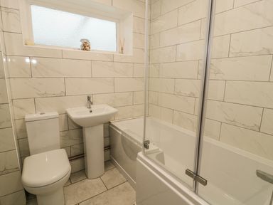 A bathroom with a toilet sink and bathtub with shower screen at Ty Taid in Rhosneigr