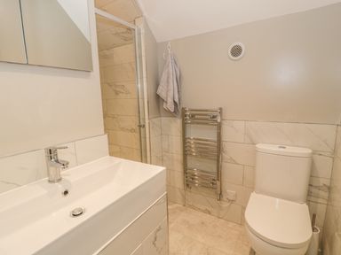 A bathroom with a sink vanity unit mirror shower towel rail and toilet at Ty Taid in Rhosneigr