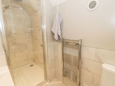 A bathroom with a shower, towel rack, and toilet at Ty Taid in Rhosneigr