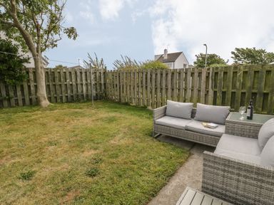 A garden with outdoor seating and a wooden fence at Ty Taid in Rhosneigr