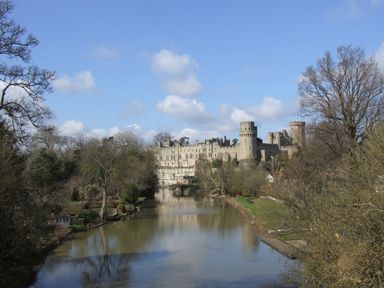 A river with trees on both sides and a large castle in the background