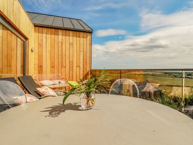 A patio with a round table and chairs overlooking fields at Stargazers in Sennen