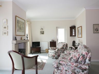 A living room with floral sofas a fireplace and a small television at Sheilas Cottage in Penryn