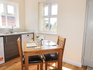 A kitchen dining area with a wooden table set for two near windows at Aln in Longframlington
