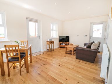 A living room with wooden furniture a sofa and a television at Aln in Longframlington