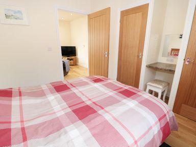 A bedroom with a bed covered in a red and white checkered duvet and wooden doors at Aln in Longframlington