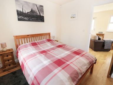 A bedroom with a wooden bed and checkered bedding next to nightstands and lamps at Aln in Longframlington