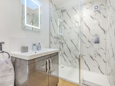 A bathroom with a sink cabinet and a walk in marble patterned shower at Old Farm Stables South Barrow near Sparkford