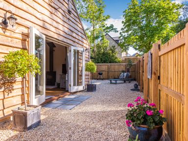 An outdoor patio with gravel ground wooden fence and open doors leading inside at Old Farm Stables South Barrow near Sparkford