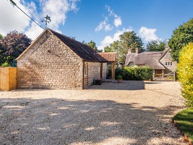 A gravel driveway with stone buildings and trees at Old Farm Stables South Barrow near Sparkford
