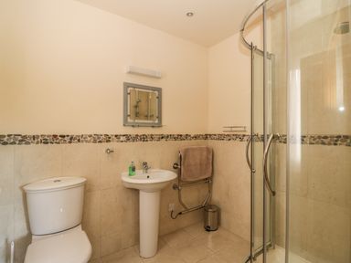 A bathroom with a toilet sink mirror glass shower and towel rail at Burnside Lodge in Aberfeldy