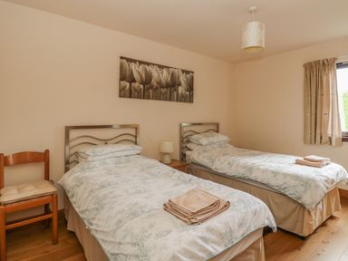 A bedroom with two single beds a wooden chair and a window at Burnside Lodge Lodge 1 Glengoulandie Aberfeldy