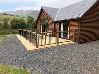 A log cabin with decking and chairs at Burnside Lodge (Lodge 1, Glengoulandie) Aberfeldy