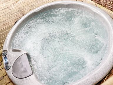 A bubbling hot tub on a wooden deck at 4 Stonerush Valley in Lanreath