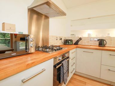 A kitchen with a microwave oven gas stove toaster kettle and knife block at 4 Stonerush Valley in Lanreath
