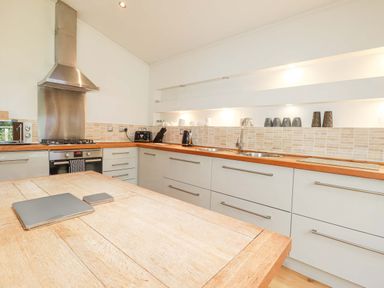 A kitchen with wooden countertops a stainless steel oven and cooker hood and a wooden table at 4 Stonerush Valley in Lanreath