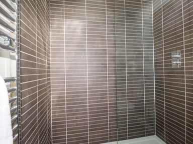 A tiled shower area with a glass door and a metal towel rack with a white towel at 4 Stonerush Valley in Lanreath