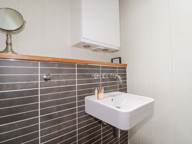 A small sink with a wall-mounted faucet and toiletry bottles in a bathroom at 4 Stonerush Valley in Lanreath