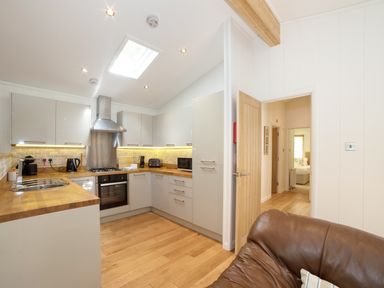 A kitchen with wooden countertops white cabinets and a brown sofa at 7 Streamside in Lanreath