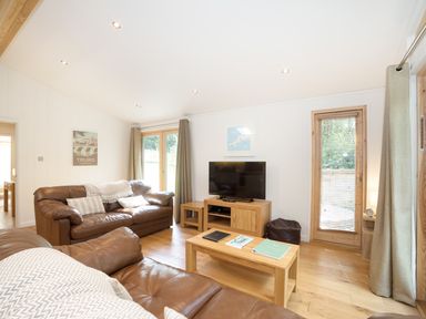 A living room with brown leather sofas a wooden coffee table and a television at 7 Streamside in Lanreath