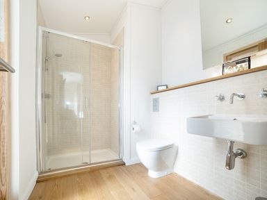 A bathroom with a shower enclosure a toilet and a wall-mounted sink at 7 Streamside in Lanreath