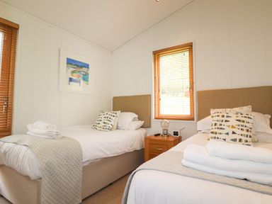 A bedroom with two single beds headboards bedside table with lamp and window blinds at 7 Streamside in Lanreath