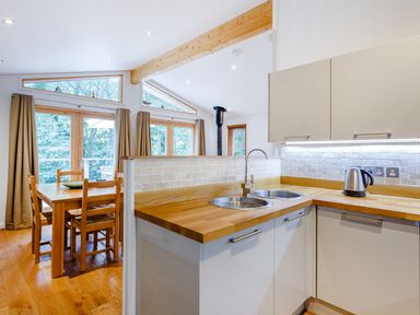 A kitchen with wooden countertops dining table and chairs near windows at 8 Streamside in Lanreath