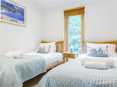 A bedroom with two single beds a wooden nightstand a window and a framed picture at 8 Streamside Lanreath