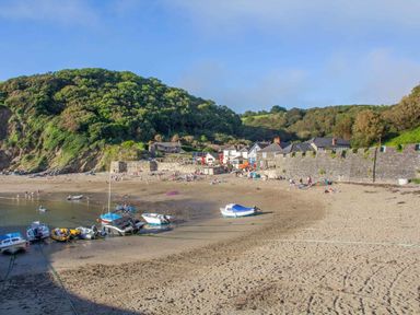 A beach with boats and people at 8 Streamside, Lanreath