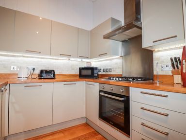 A kitchen with cabinets a wooden countertop a kettle a toaster a microwave an oven a gas stove and a knife block at 2 Stonerush Valley Lanreath