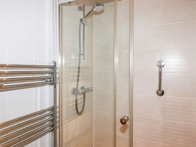 A shower enclosure with a glass door a wall-mounted showerhead and a chrome towel radiator at 2 Stonerush Valley in Lanreath