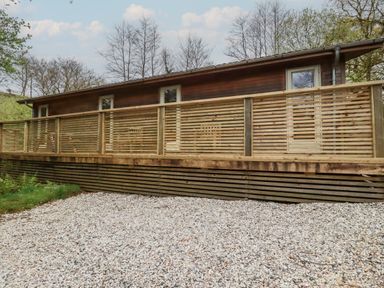 An exterior view of a wooden house with horizontal slatted railings and gravel ground at 2 Stonerush Valley in Lanreath