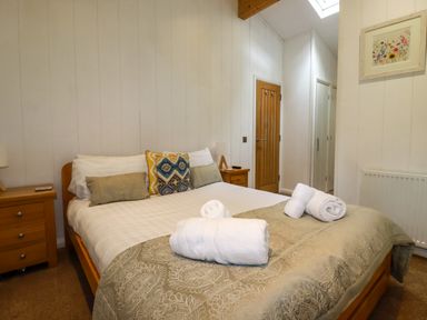 A bedroom with a double bed two bedside tables and a framed picture on the wall at 2 Stonerush Valley Lanreath